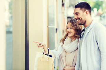 Image showing happy couple with shopping bags at shop window