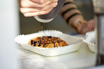 Image showing close up of cook adding syrup to waffle