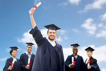 Image showing students or bachelors with diplomas over blue sky