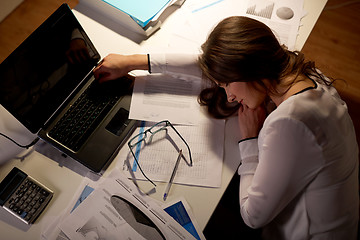 Image showing tired woman sleeping on office table at night