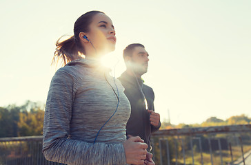 Image showing happy couple with earphones running outdoors