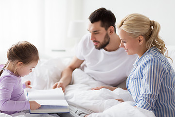 Image showing happy family reading book in bed at home