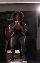 Image showing black female athlete is performing box jumps at gym