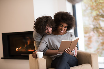 Image showing multiethnic couple hugging in front of fireplace