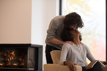 Image showing multiethnic couple hugging in front of fireplace