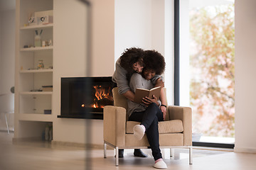 Image showing multiethnic couple hugging in front of fireplace