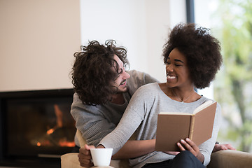 Image showing multiethnic couple hugging in front of fireplace