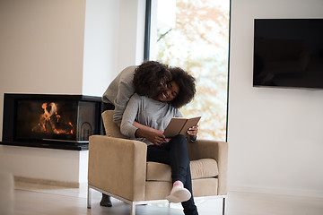 Image showing multiethnic couple hugging in front of fireplace