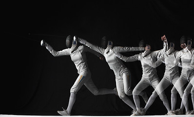 Image showing Full-length portrait of woman wearing white fencing costume on black