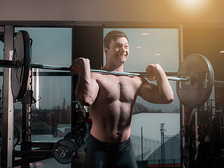 Image showing Portrait of super fit muscular young man working out in gym with barbell