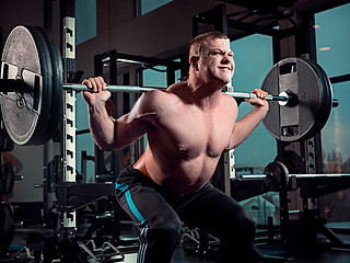 Image showing Portrait of super fit muscular young man working out in gym with barbell