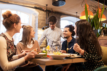 Image showing happy friends eating and drinking at restaurant