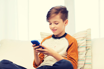 Image showing boy with smartphone texting or playing at home