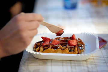 Image showing close up of woman eating waffle with strawberry