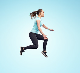 Image showing happy smiling sporty young woman jumping in air