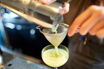 Image showing bartender pouring cocktail into glass at bar