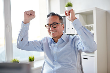 Image showing happy businessman celebrating victory at office