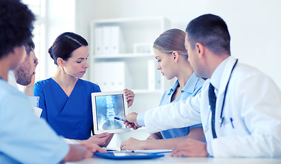 Image showing group of doctors with x-ray on tablet pc at clinic
