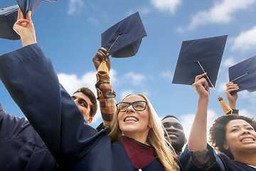 Image showing happy bachelors waving mortar boards over sky