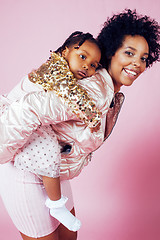 Image showing young pretty african-american mother with little cute daughter hugging, happy smiling on pink background, lifestyle modern people concept 