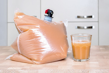 Image showing Plastic bag and glass full of apple juice