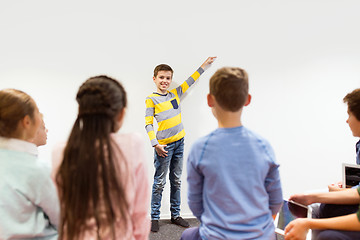 Image showing happy student boy showing something at white wall