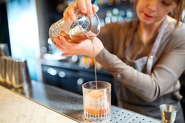 Image showing bartender with glass and jug preparing cocktail