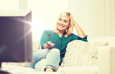 Image showing smiling woman with remote watching tv at home