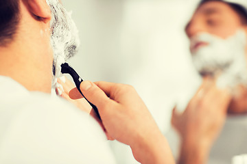 Image showing close up of man shaving beard with razor blade