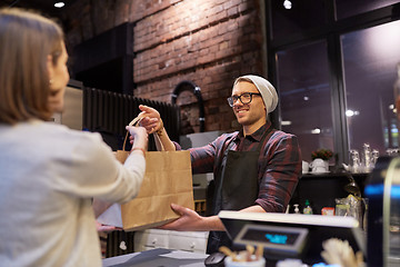 Image showing woman taking paper bag from seller at cafe