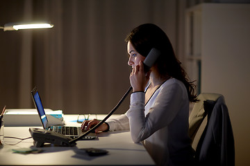 Image showing woman with laptop calling on phone at night office