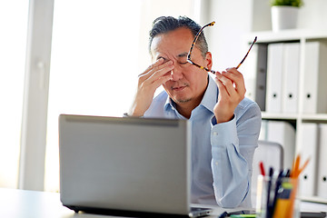 Image showing tired businessman with glasses at laptop in office