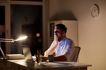 Image showing man with laptop and coffee working at night office