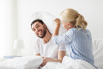Image showing happy couple having pillow fight in bed at home