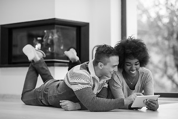 Image showing multiethnic couple used tablet computer on the floor