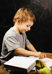 Image showing little cute boy with young teacher in classroom studying at blac