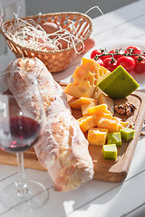 Image showing Wine, baguette and cheese on wooden background