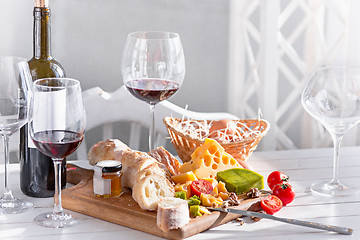 Image showing Wine, baguette and cheese on wooden background