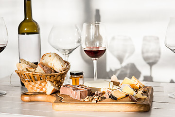 Image showing Wine, baguette and cheese on wooden background