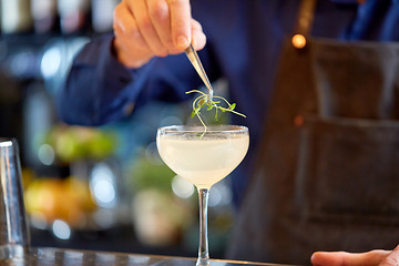 Image showing bartender decorating glass of cocktail at bar