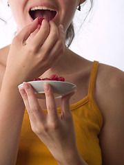 Image showing Girl eating raspberry