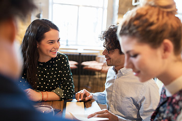 Image showing happy friends looking to menu at restaurant