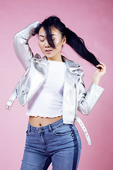 Image showing young pretty smiling asian korean girl wearing modern fashion clothers on pink background, lifestyle people concept 