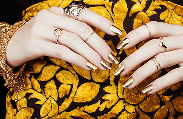 Image showing woman hands with golden manicure lot of jewelry on fancy dress close up
