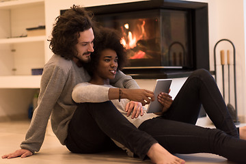 Image showing multiethnic couple using tablet computer on the floor