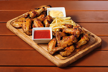 Image showing Big wooden board with grilled chicken winds