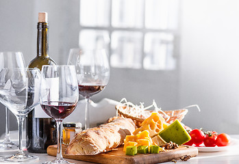 Image showing Wine, baguette and cheese on wooden background