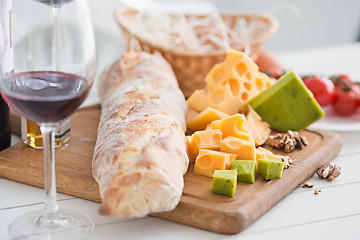 Image showing Wine, baguette and cheese on wooden background