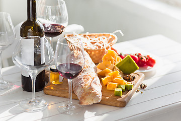 Image showing Wine, baguette and cheese on wooden background