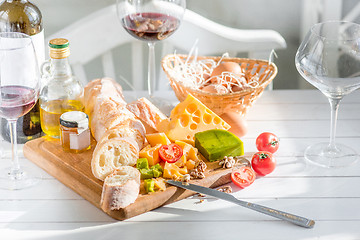 Image showing Wine, baguette and cheese on wooden background